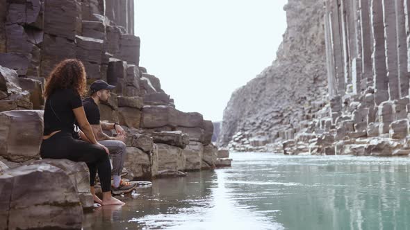 Tourists Sitting by Rocks in the River of Studlagil Canyon, Iceland alt
