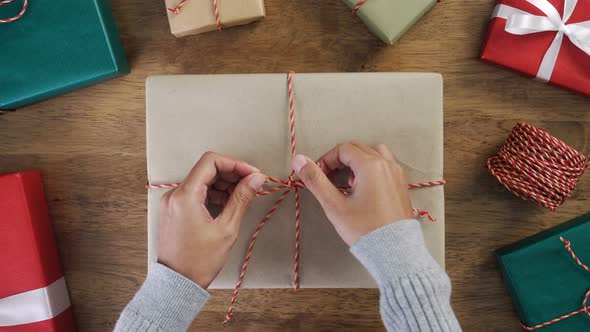 Woman hands tying gift box with string on wood table