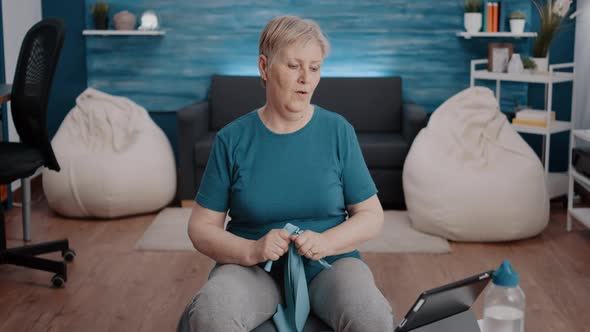 Old Woman Watching Online Workout Program on Tablet alt