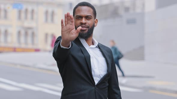 Serious Strong Decisive African Bearded Young Adult Ethnic Male Puts Palm in Front of Him alt