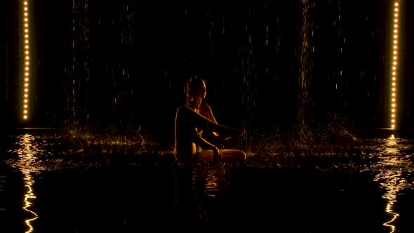 Exercise the Leg Behind the Head. Young Woman Practices Yoga Asanas in a Dark Studio in the Rain alt