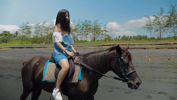 Cute Chinese Teenager Rides a Horse On The Beach In Bali alt