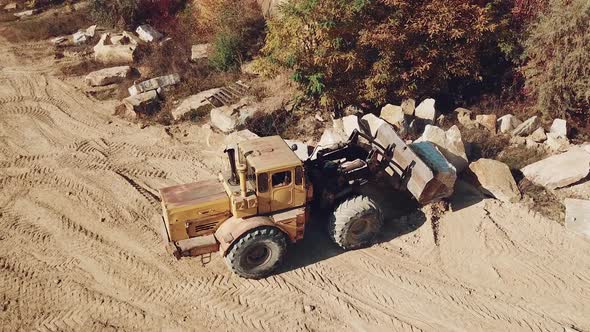 specially equipped machine with a bucket id working near a quarry with stones alt