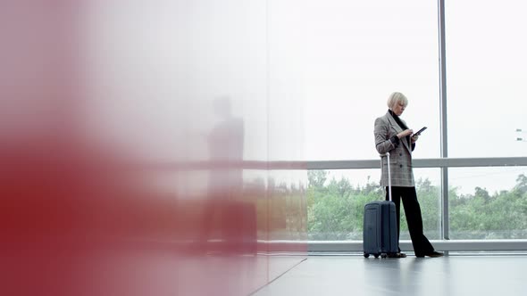 A General Slow Motion Shot of a Blonde Executive Woman Standing in the Airport Terminal with a Hand