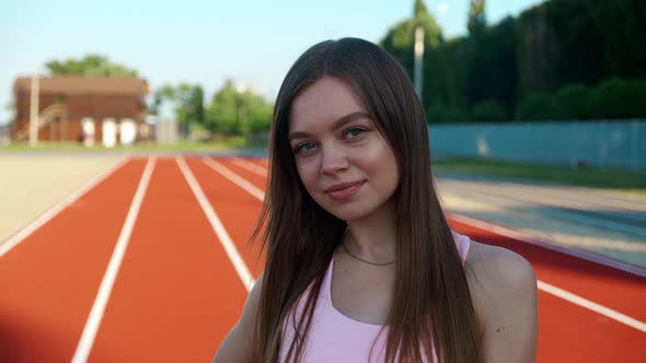 Attractive Woman Standing on Red Sport Track and Looking at Camera alt