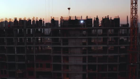 In the Background Working Crane and City. Aerial Shot of the Building in the Process of Construction