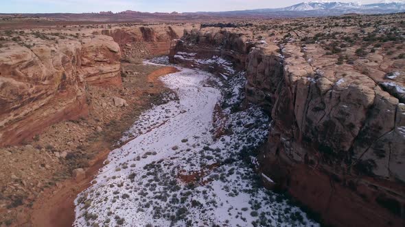 Flying over desert canyon past slack line across the rim of the canyon alt