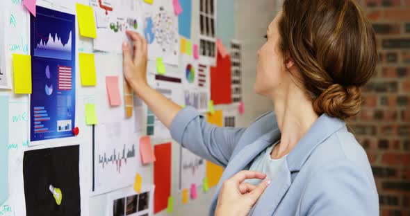 Female business executive looking at a whiteboard alt
