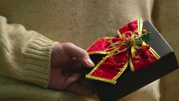 Close Up of Young Man Holding Present Behind His Back alt