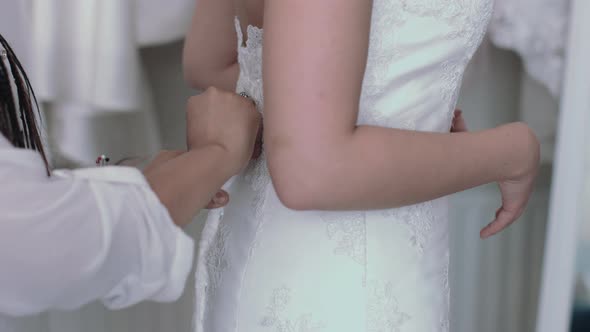 Young entrepreneur helping bride with dress fitting