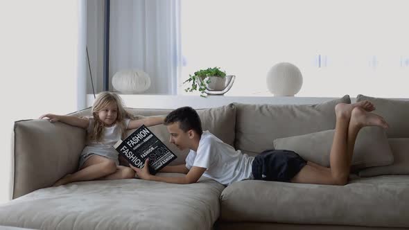 Brother Reading a Book to His Sister Lying on the Sofa