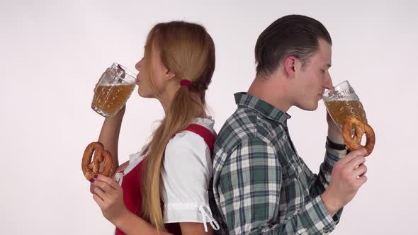Bavarian Woman and Her Man Enjoying Beer with Pretzels alt