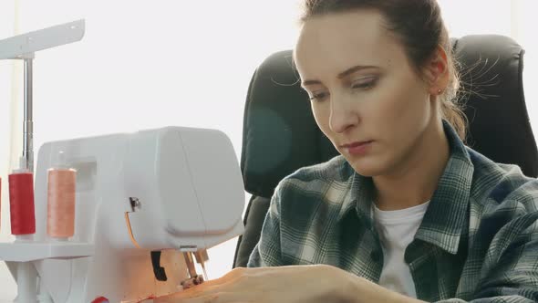Close up of professional woman tailor sews on sewing machine. alt