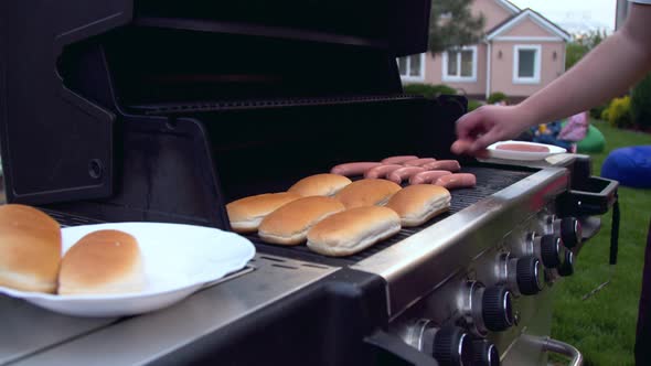 Man Preparing Hot Dogs on a Grill