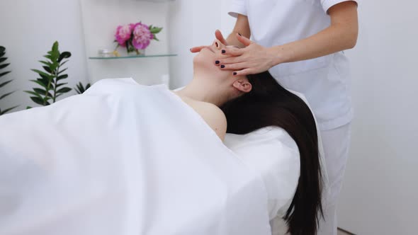 Relaxed Woman Lying on Spa Bed for Facial and Head Massage Spa Treatment by Massage Therapist