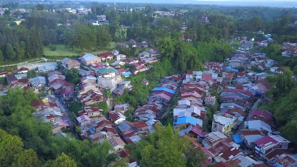 Scenic fly over a poor friendly neigbourhood rooftop surrounded by beautiful trees and natural green alt