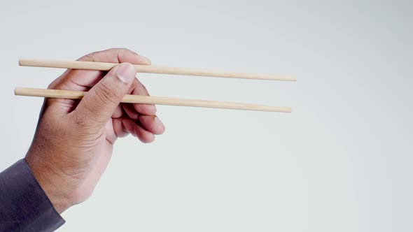 Hand Holds Wooden Chopsticks  alt