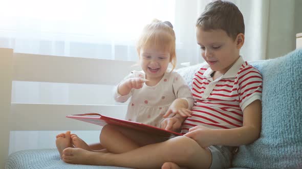 Brother and Sister Reading a Book on the Bed alt