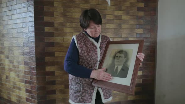 Senior 60s Woman Wipe Old Photo Portrait of an Ancestor