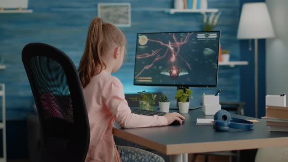 Young Child Playing Action Video Games on Computer at Desk, Stock