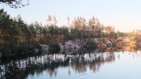 View of a Beautiful Clear Lake Among Granite Rocks and Pine Forest Reflected in the Water at Sunset