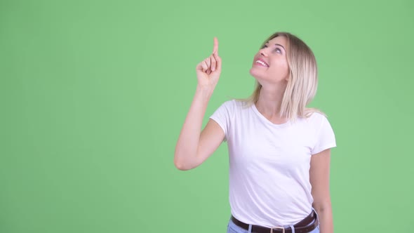 Happy Young Beautiful Blonde Woman Pointing Up and Looking Excited alt
