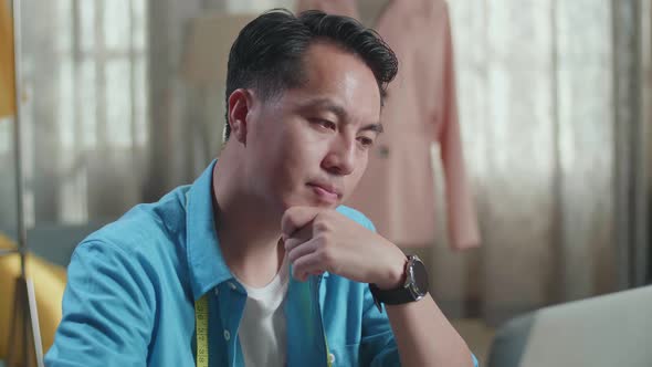 Asian Male Designer Working On A Laptop And Thinking Then Raising Index Finger While Designing alt