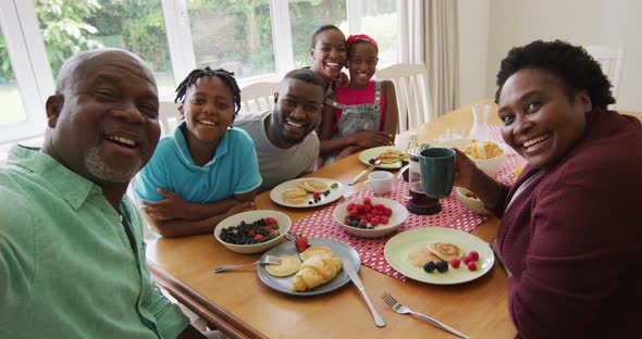 Three generation african american family taking a selfie while having breakfast together at home alt