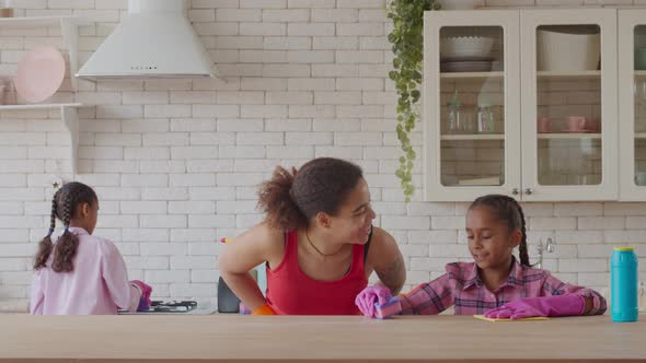 African Daughters Helping Mother Cleaning Kitchen alt