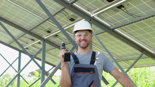 Male Engineer in Protective Helmet Installing Solar Photovoltaic Panel System Using Screwdriver alt