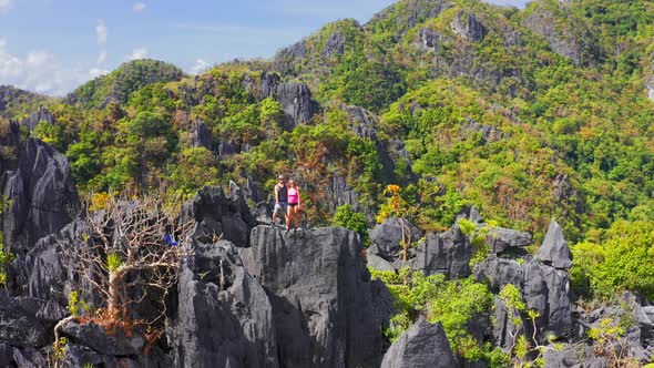 Couple Family Traveling Together on Cliff Edge Taraw in El Nido, Philippines. Man and Woman alt