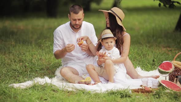 Parents and Their Son Eating Bakery at Picnic.