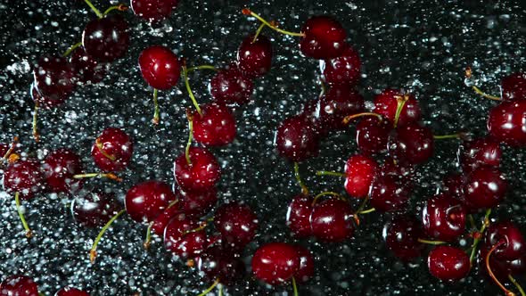 Super Slow Motion Shot of Flying Fresh Cherries and Water Side Splash at 1000Fps. alt