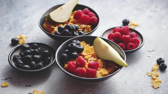 Golden Cornflakes with Fresh Fruits of Raspberries Blueberries and Pear in Ceramic Bowl alt
