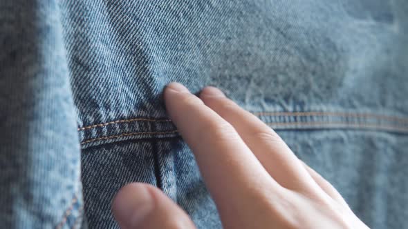 Hand of a Caucasian Person Touches Blue Denim Jeans Jacket