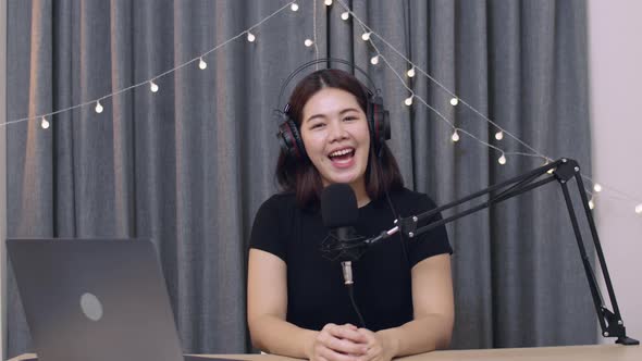 Asian female influencer recording a vlog using podcast microphone.