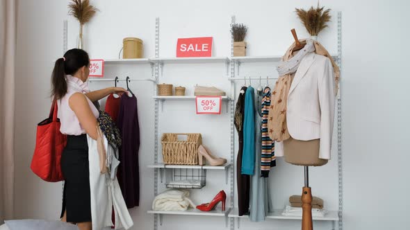 Shopaholic Woman Grabbing Lot of Clothes on Sale alt