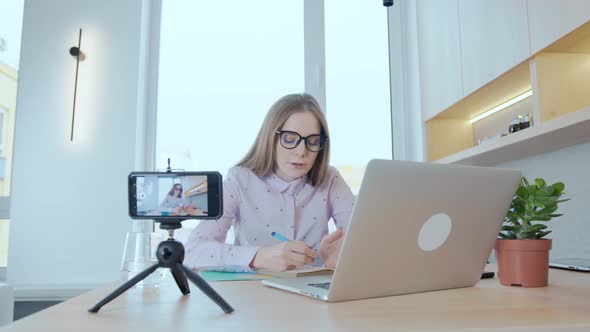 Young woman at home holding an online conference using a smartphone, chatting online alt