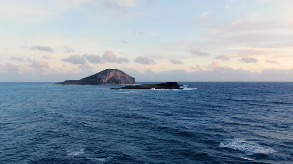 Drone flying toward mini islands in hawaii during a beautiful sunrise alt