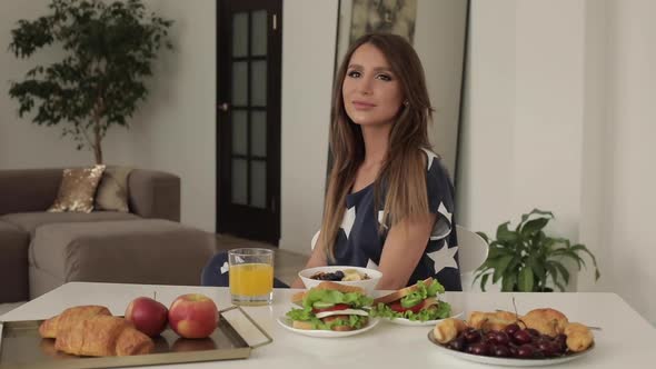 Beautiful Young Woman Sitting on Table with Appetizing Tasty Breakfast Medium Shot