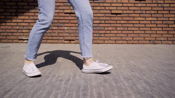 Pretty Woman Counts and Dances Near Red Brick Wall on Street