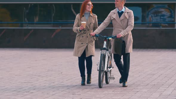 Coworkers going with bicycle and coffee