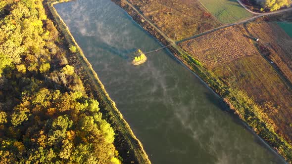 flying with drone over an artificial island in the lake during foggy morning alt