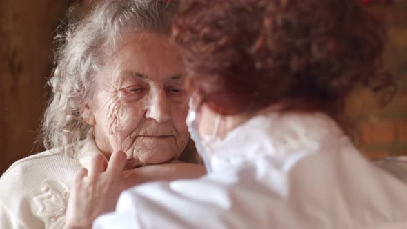 Woman Doctor with Stethoscope Listens to an Elderly Patient Old Woman and Talks Comforting Her alt
