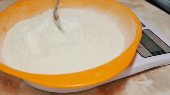 The Baker Mixes Dry Ingredients in an Orange Bowl with a Spoon Flour Sugar Salt and Baking Powder
