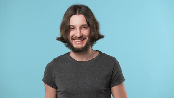 Portrait of Young Hairy Man 20s Wearing Casual Gray Tshirt and Necklace Smiling Broadly in Good Mood alt