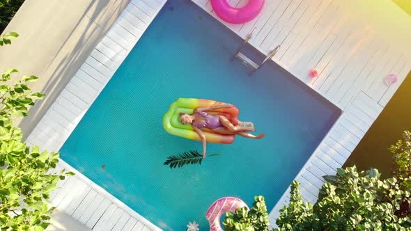 A Young Woman Relaxes in the Pool alt