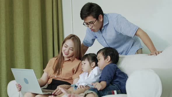 Asian family watching a laptop on the sofa