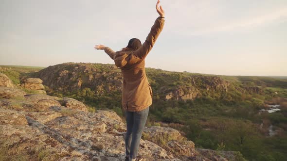 A Young Woman Traveler Walks in the Mountains at Canyon alt