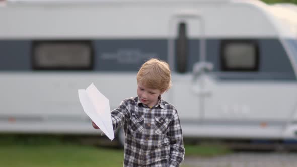 Young Blond Boy Plays with the Paper Plane During the Holidays.